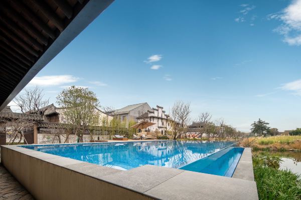 Outdoor pool area with surrounding seating and greenery.