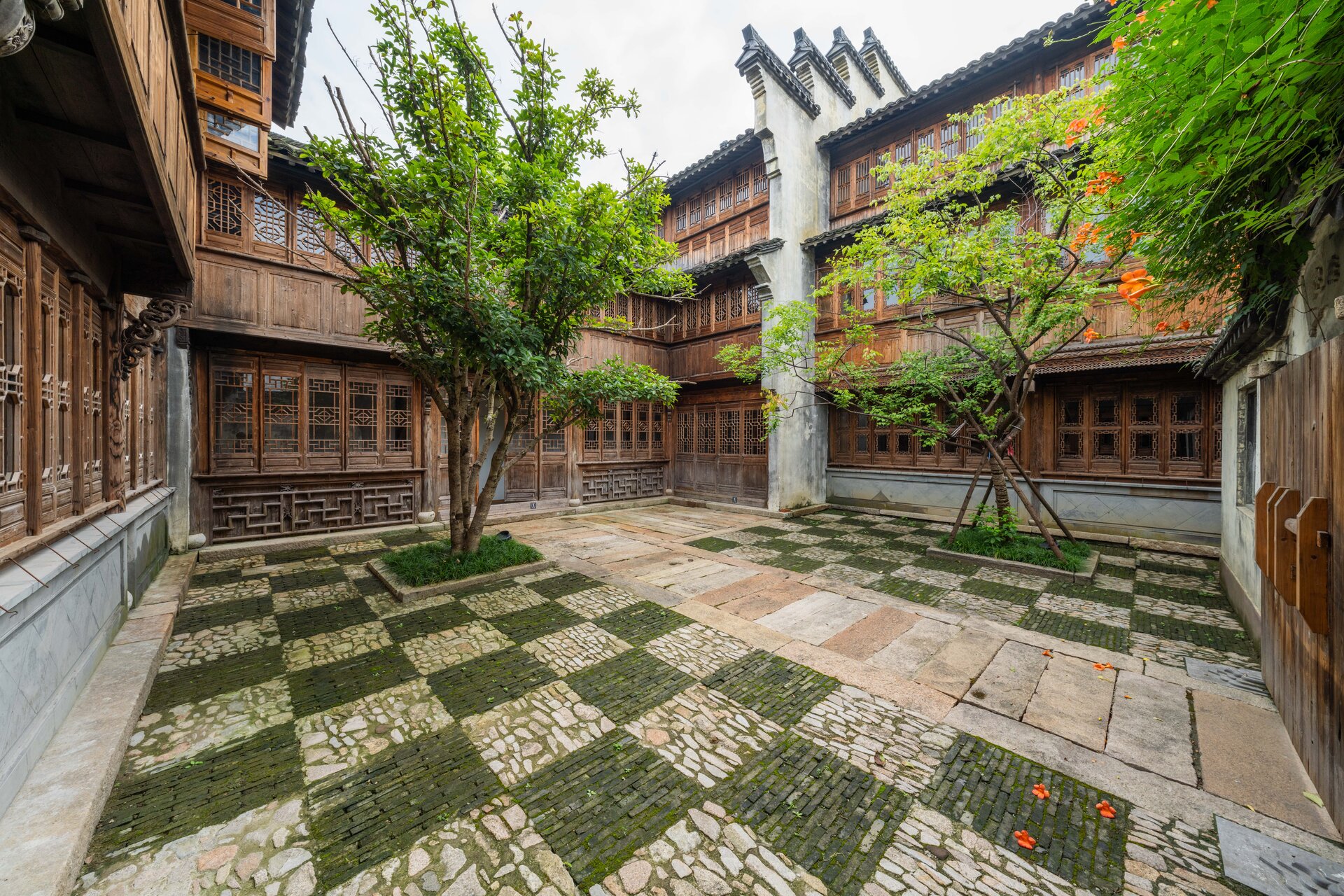 The interior courtyard features an ancient and rustic atmosphere with lush green trees.