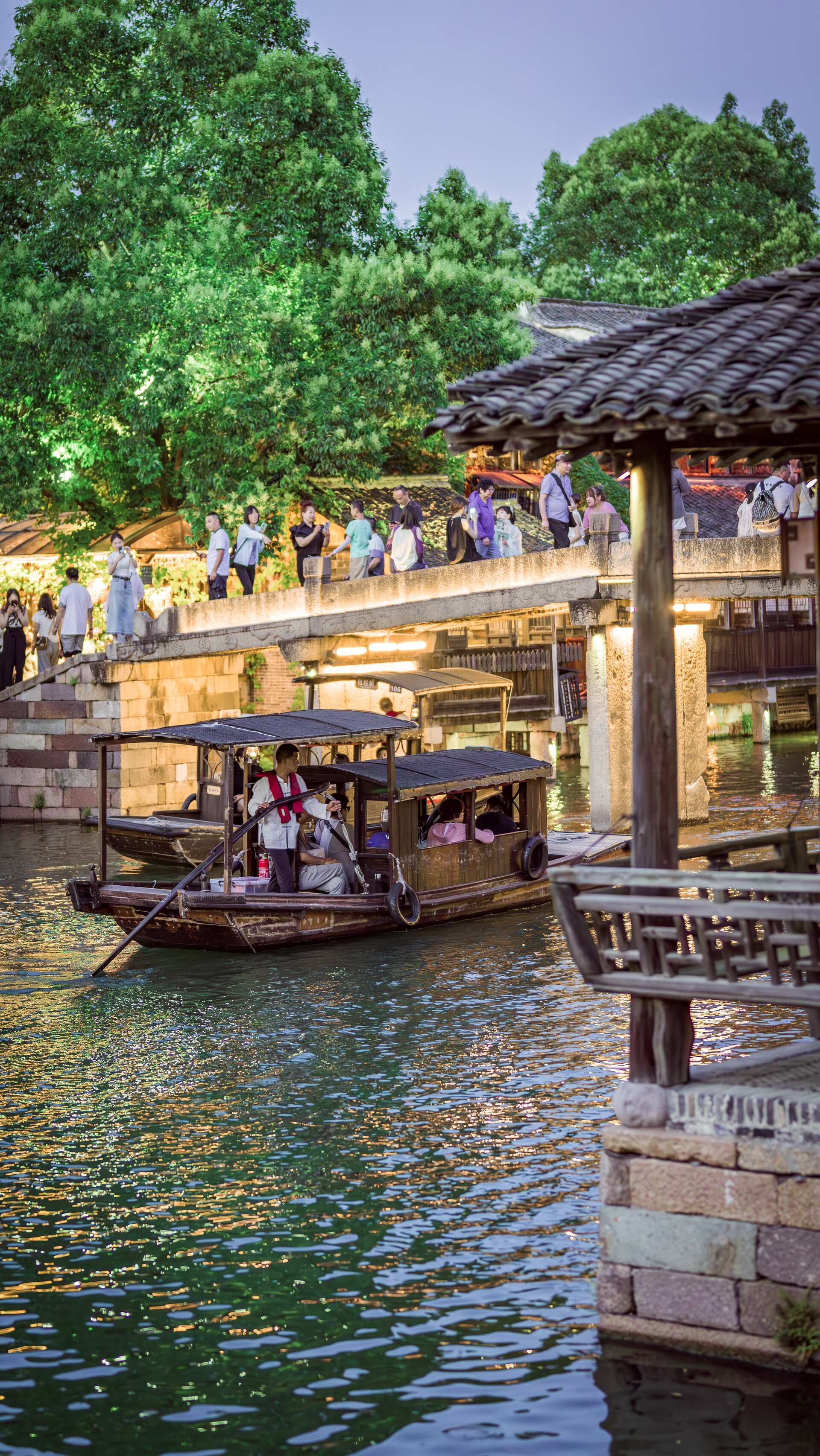 Illuminated wuzhen water town canal with passenger boats.