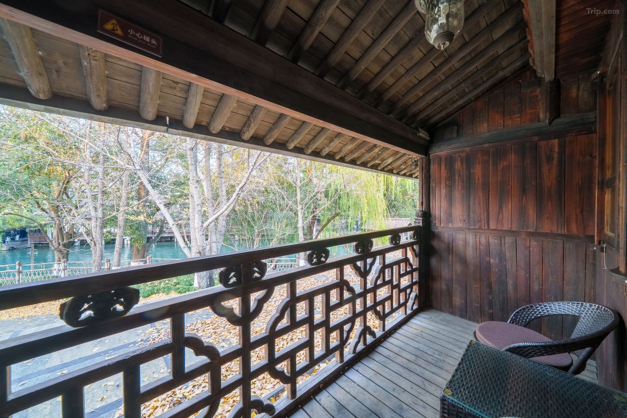 Wooden balcony corridor with views over lush greenery and tiled roofs.