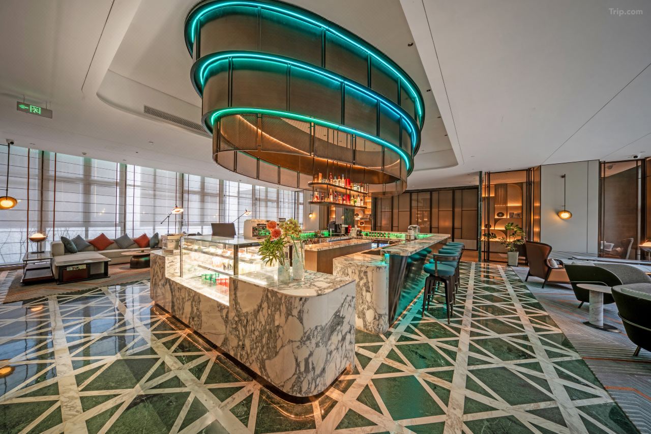 A stylish hotel bar with curved lighting features, bar seating, and a vibrant, contemporary interior design.