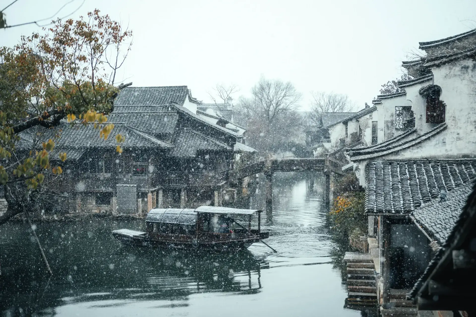 Jiangnan water town covered in winter snow with wooden tour boat.