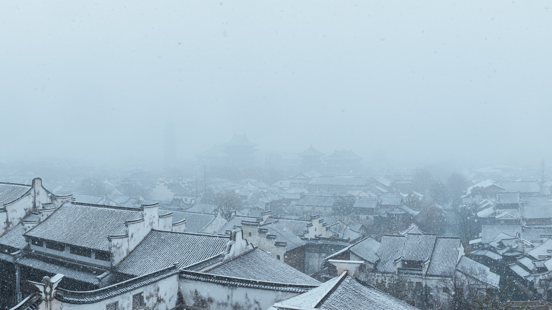 Aerial view of Puyuan water town shrouded in drifting winter snow and fog.