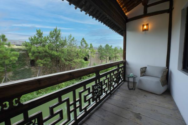 A balcony view overlooking traditional tiled rooftops and lush greenery, offering a peaceful and scenic outlook.