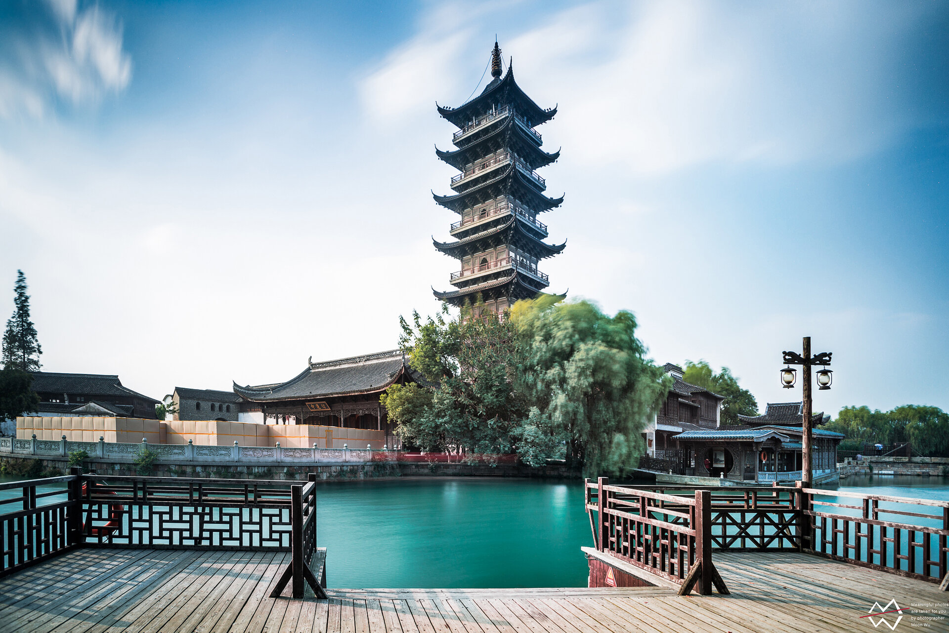 Wuzhen white lotus pagoda standing by calm green water.