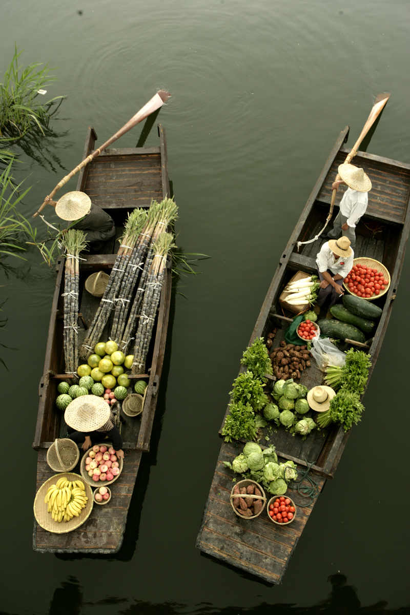 Small wooden market boats piled with fresh farm produce.