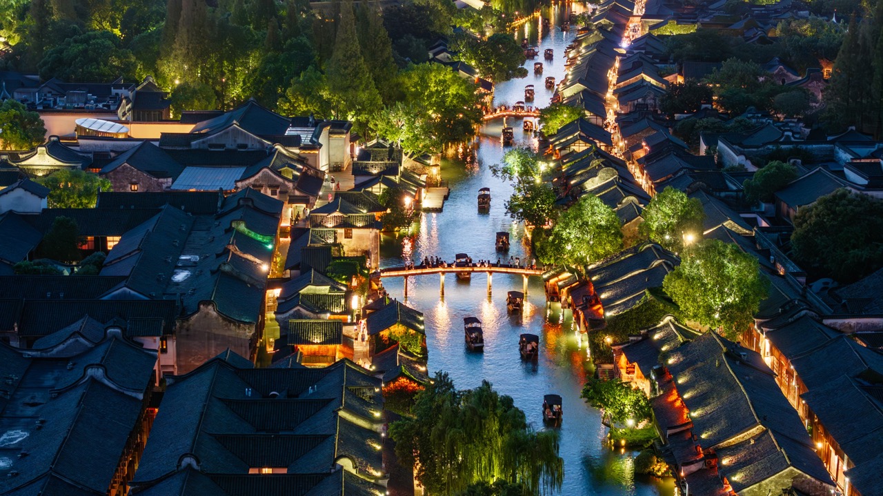 Busy Wuzhen Xizha waterway full of glowing boats at night.