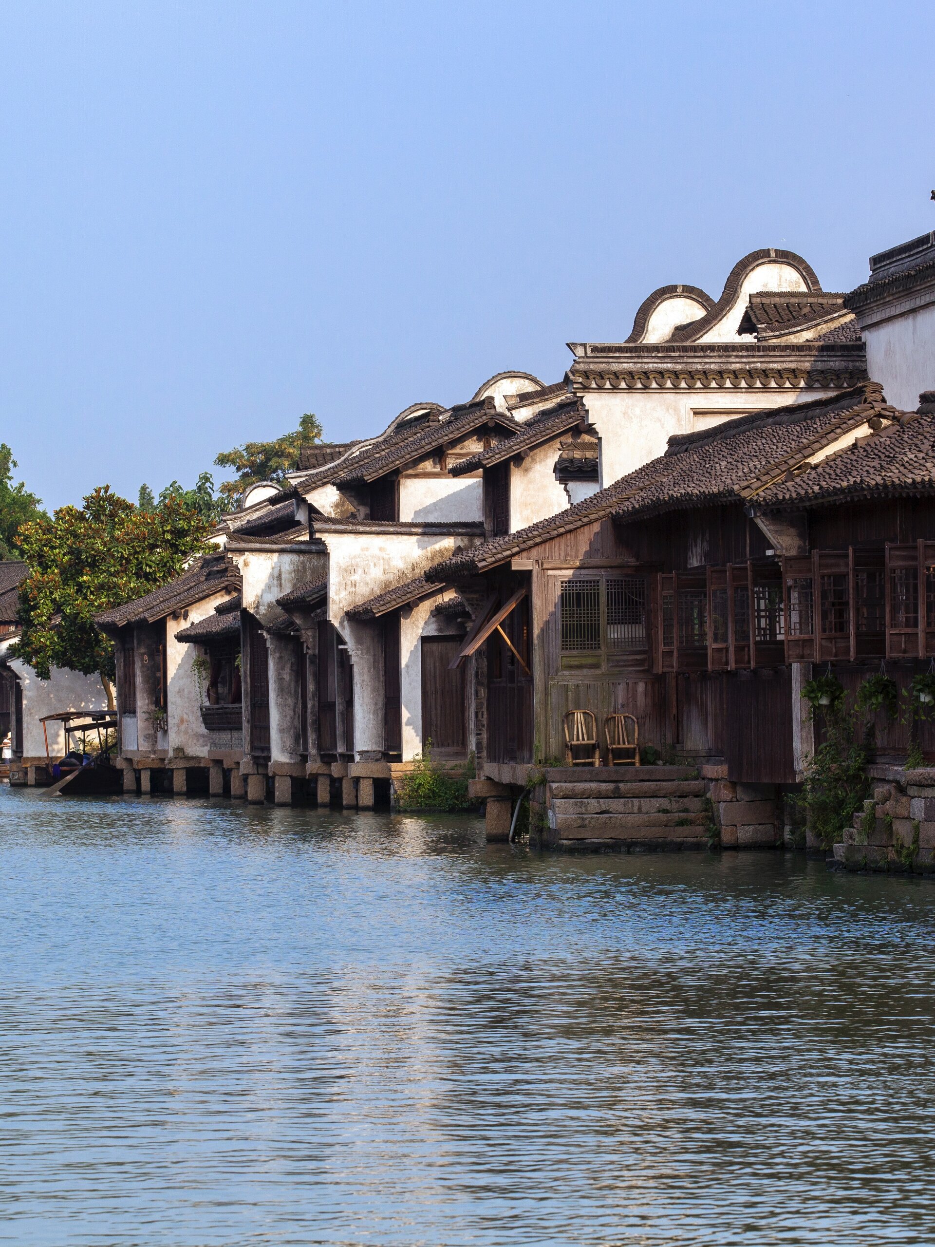 White wall & timber waterside houses built on stone stilts along canal.
