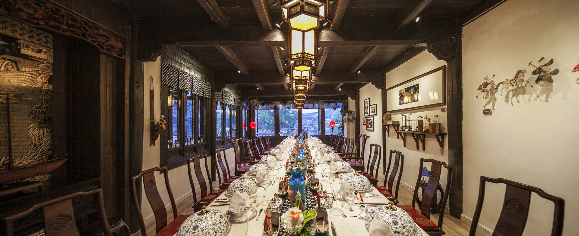 Long banquet table set with Chinese tableware in a traditional wood-beamed dining room