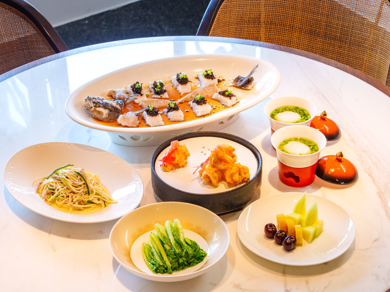 Classic local dishes: steamed perch with black fungus, crispy prawn rolls, shredded pork cold dish and seasonal vegetables served on elegant porcelain tableware.