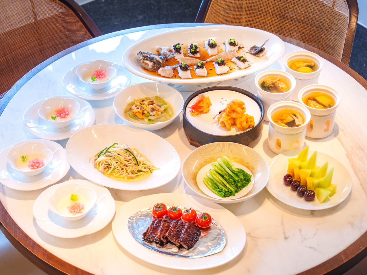 Full set of banquet dishes including roast ribs, seafood soup, seasonal cold dishes and fruit platters prepared for group dinner at Dan Cha Fun.