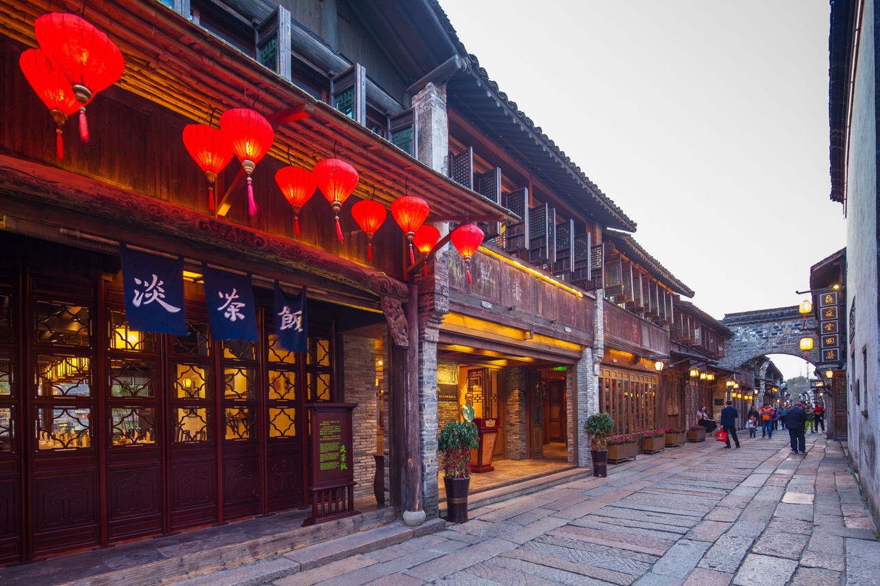 Exterior view of Dan Cha Fun along Wuzhen ancient stone street, decorated with rows of red lanterns and blue vertical sign banners.