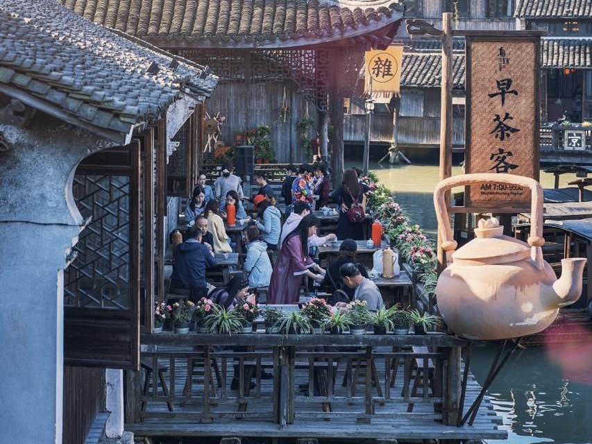 Waterside morning tea stall "Early Tea Guests" in Wuzhen Xizha, visitors enjoying breakfast tea under ancient tiled roofs