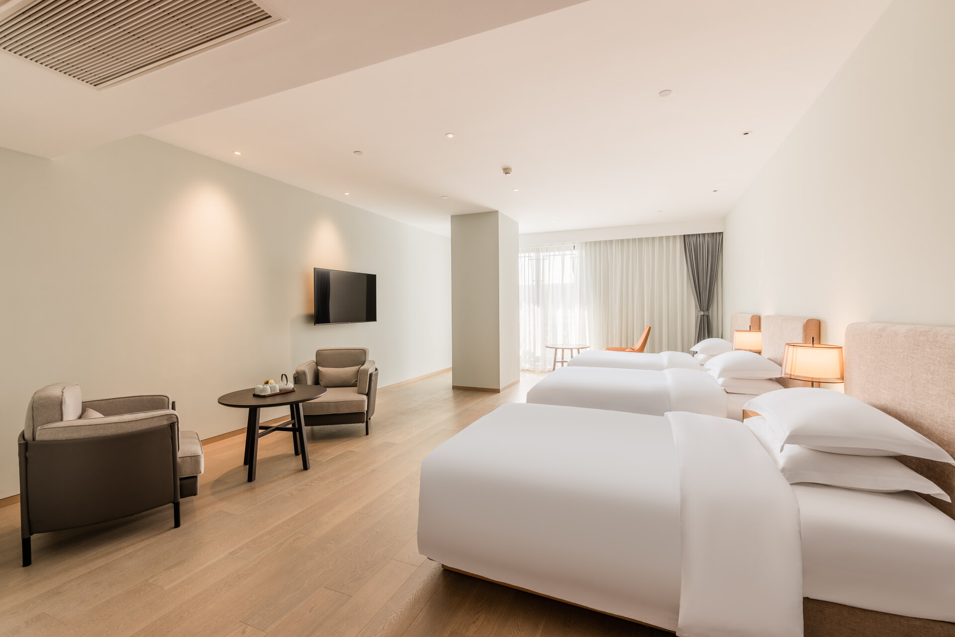 Interior of a deluxe triple room with three beds and spacious layout.