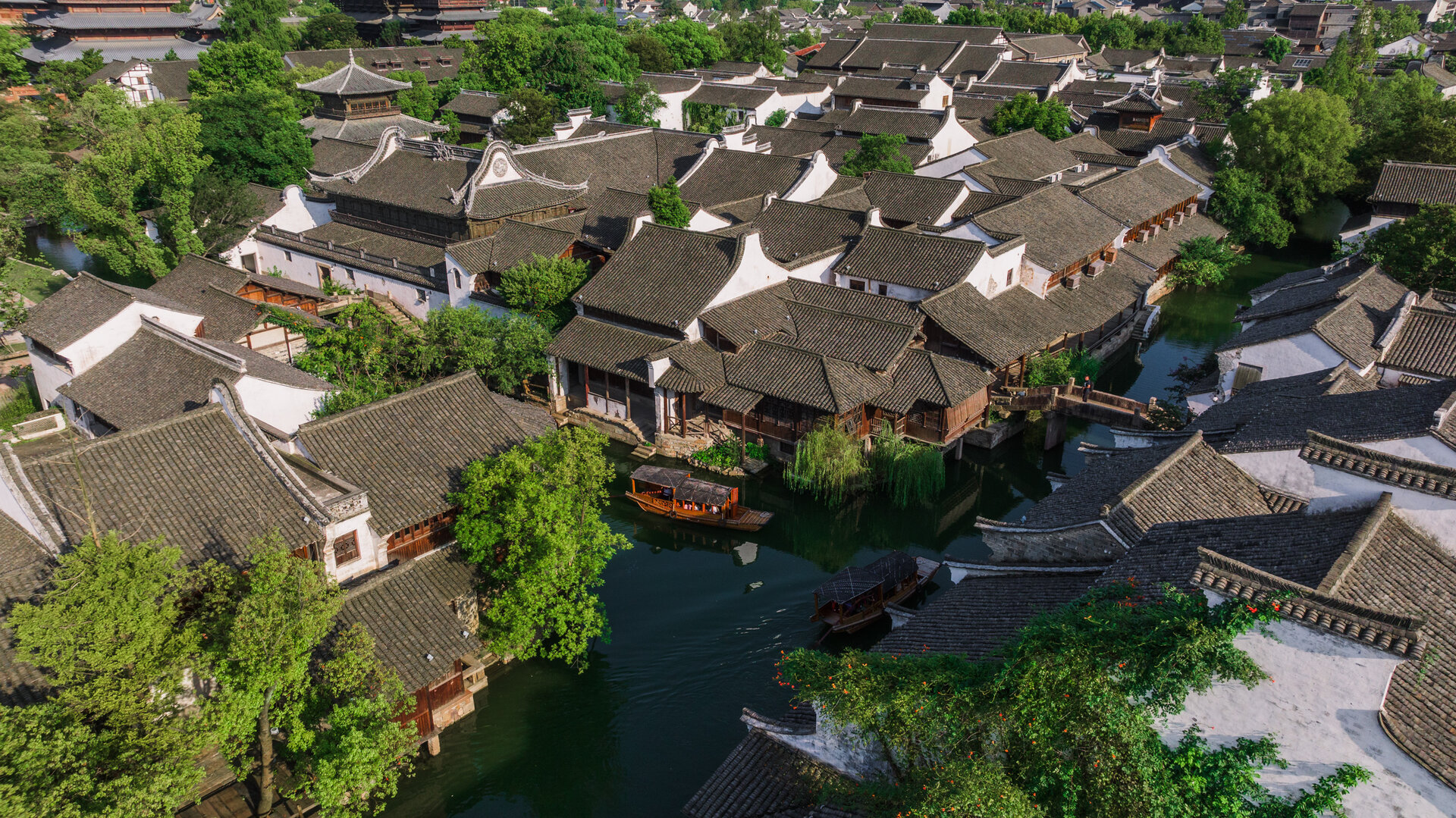 Bird's-eye view of wuzhen water town with black tiled roofs and covered tour boats.