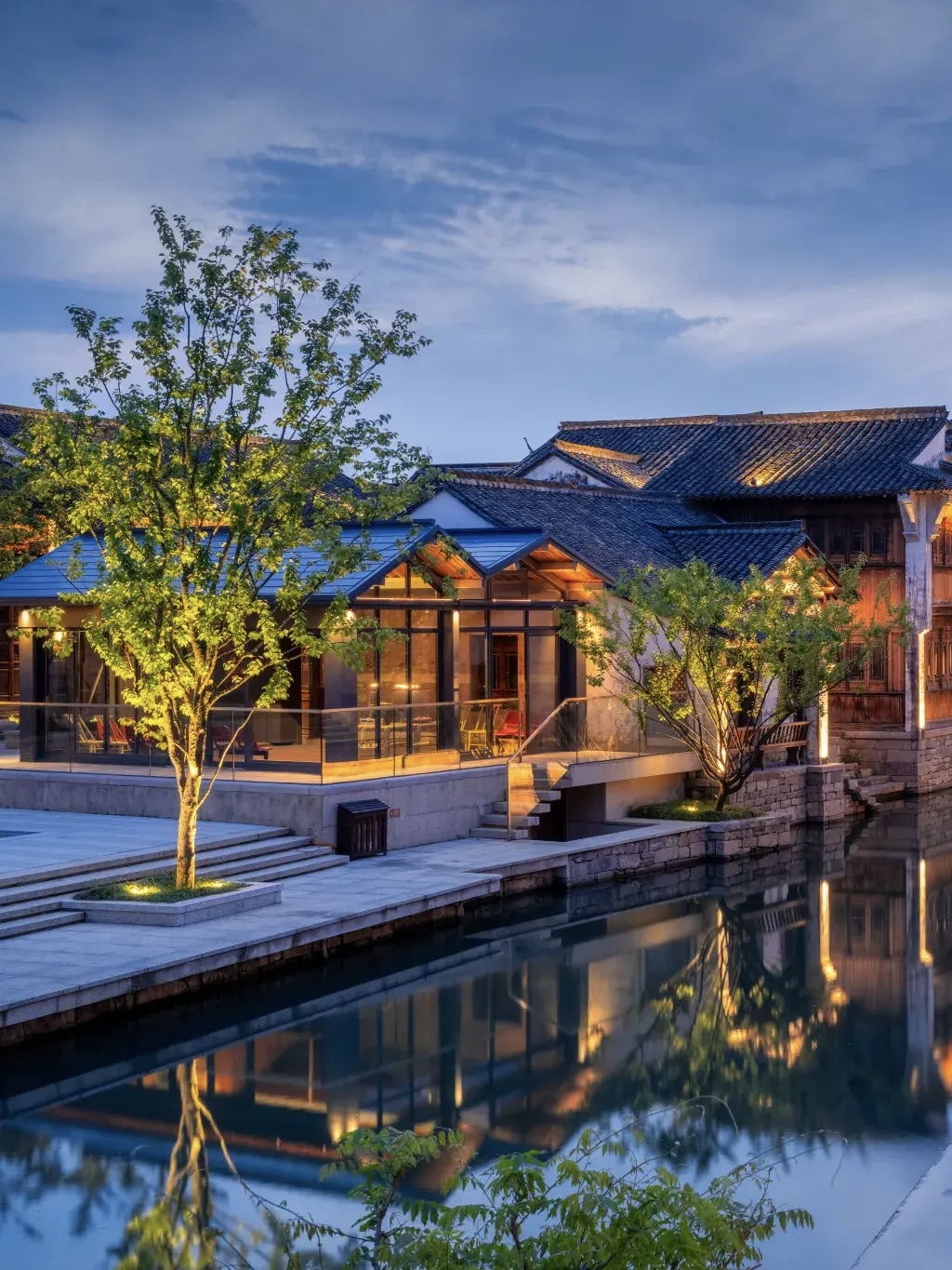 Modern glass annex attached to historic riverside houses in Puyuan.