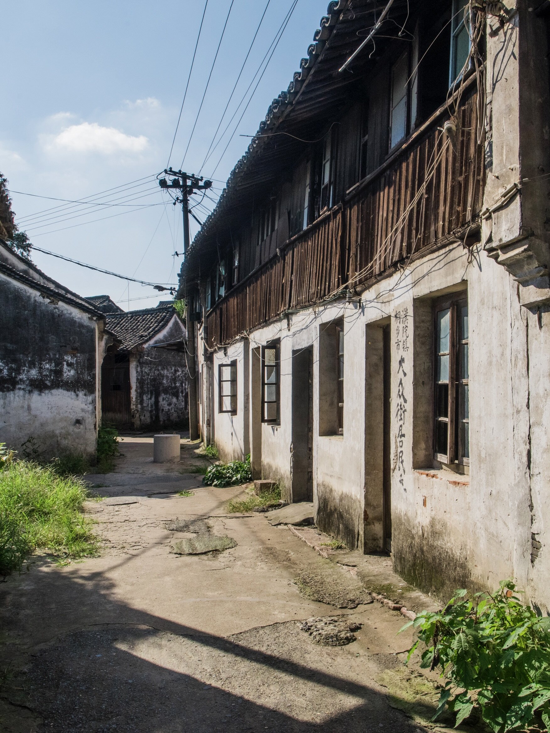 Weathered two-story wooden dwellings in ancient Puyuan lane, old residential site mark on wall.