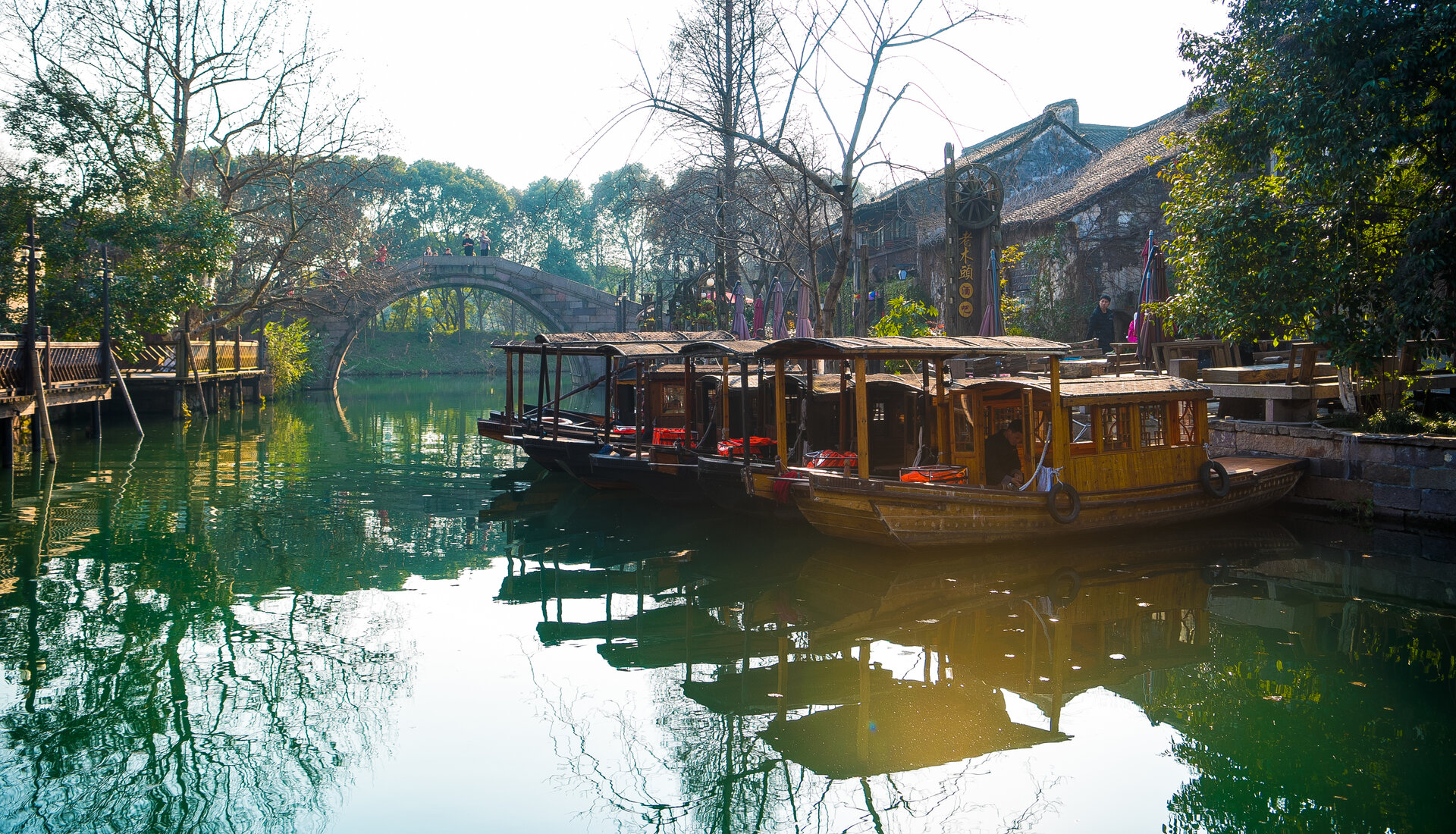 Parked wuzhen covered traditional boats reflecting in calm canal.