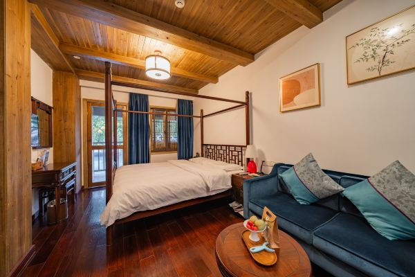 Traditional wooden double room with canopy bed, seating area and balcony view.