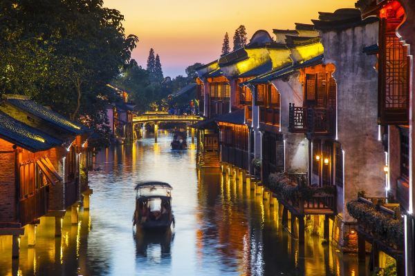 Night view of Wuzhen canal with illuminated buildings and passing boats.