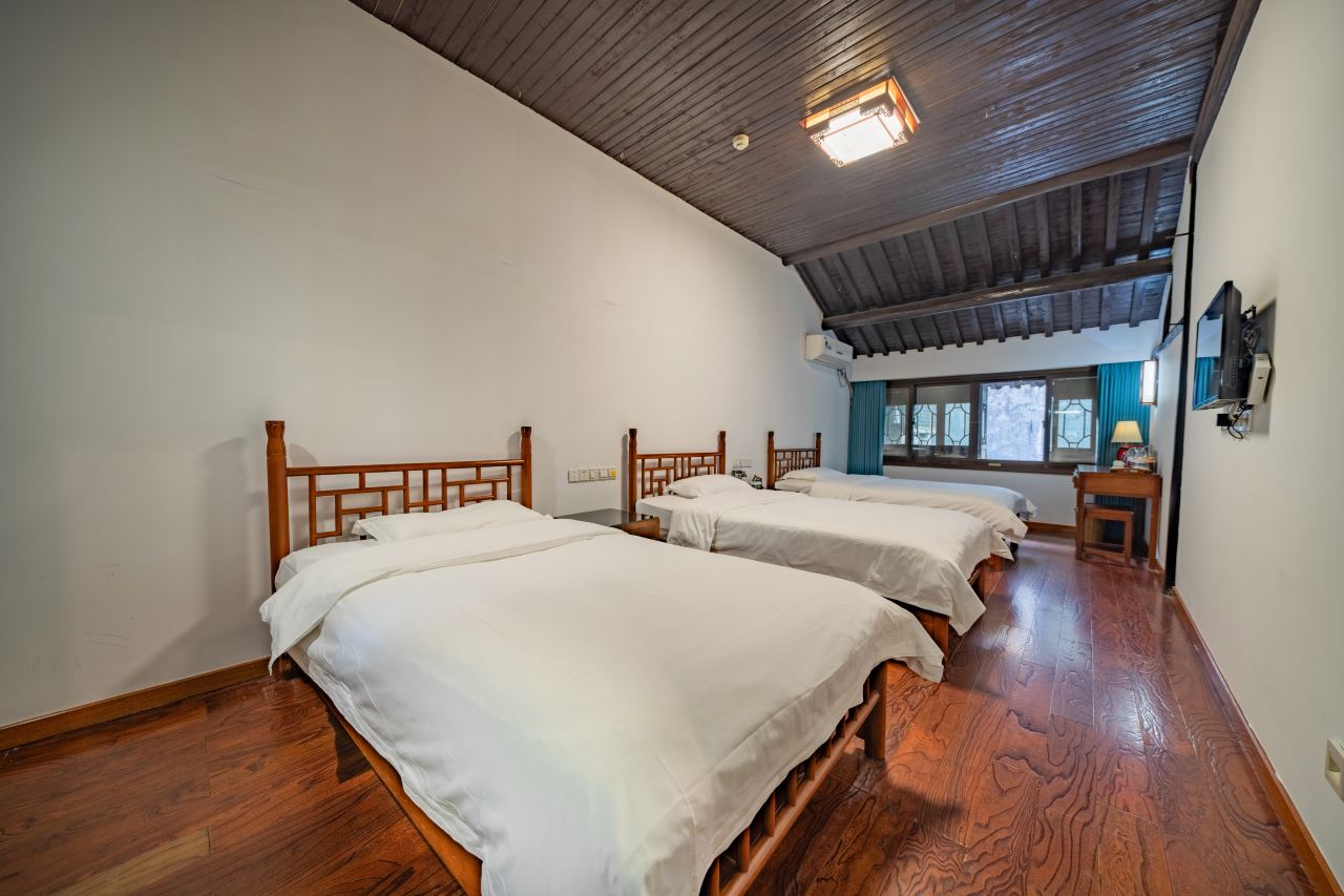Spacious triple room with three single beds and wooden flooring.