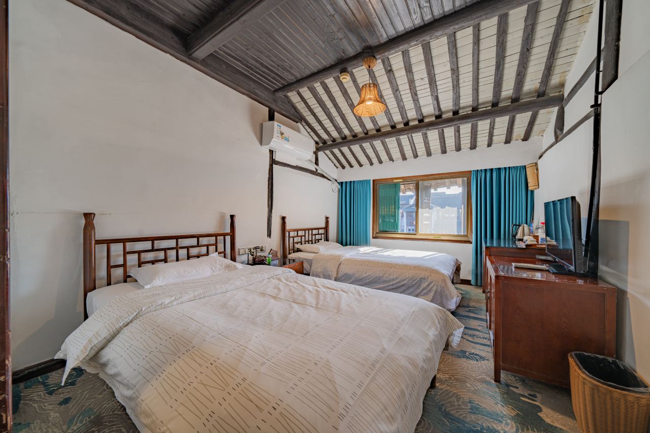 Twin room with two beds, wooden beams and window with natural light.