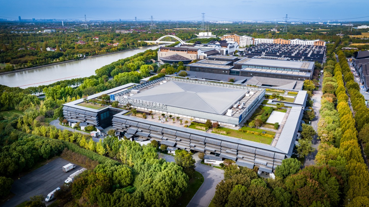 Panoramic aerial shot of Wuzhen World Internet Conference Exhibition Center beside river, Jiangnan-style roof design.