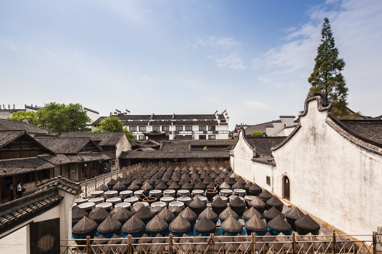 Rows of covered clay sauce vats laid out in open courtyard of ancient sauce workshop.
