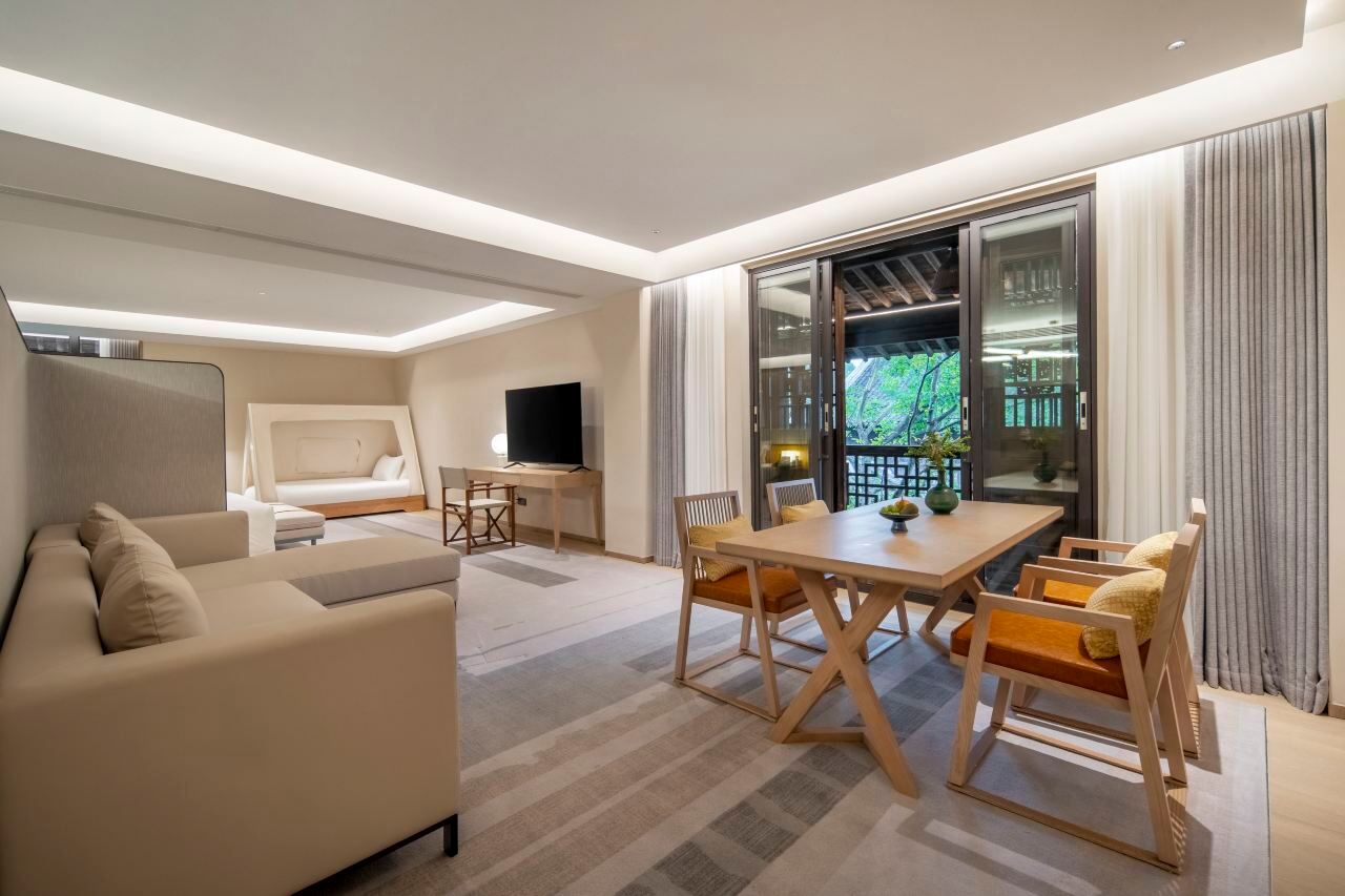 A well-appointed suite featuring a living area, sofa seating, and large windows allowing natural light to fill the space.