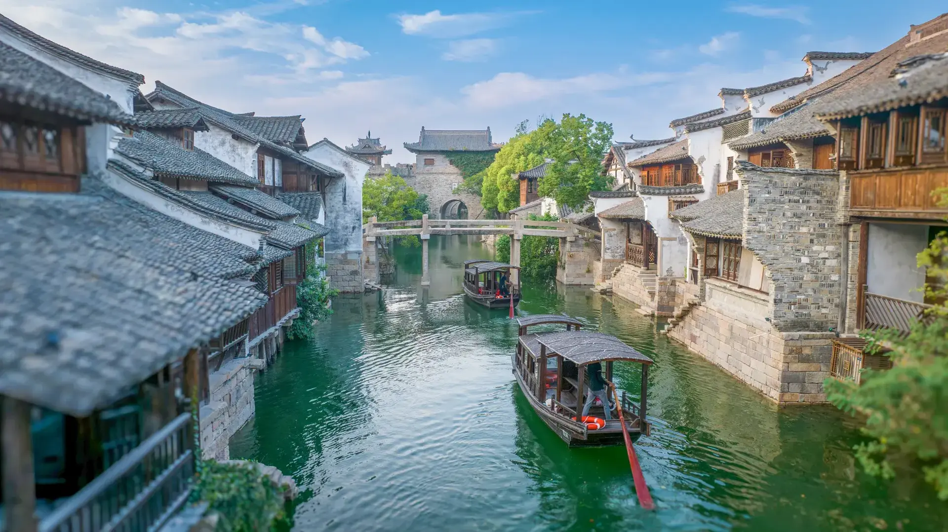 Traditional covered wooden boats sailing through Yanguan water town canal.
