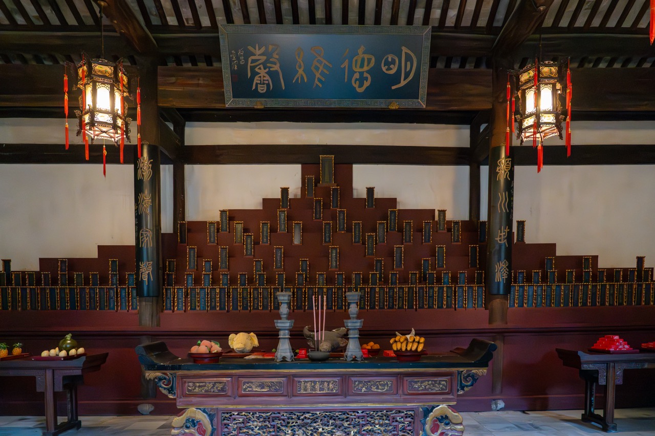 Traditional ancestral hall with memorial tablets, carved offering altar and ancient Chinese plaque.