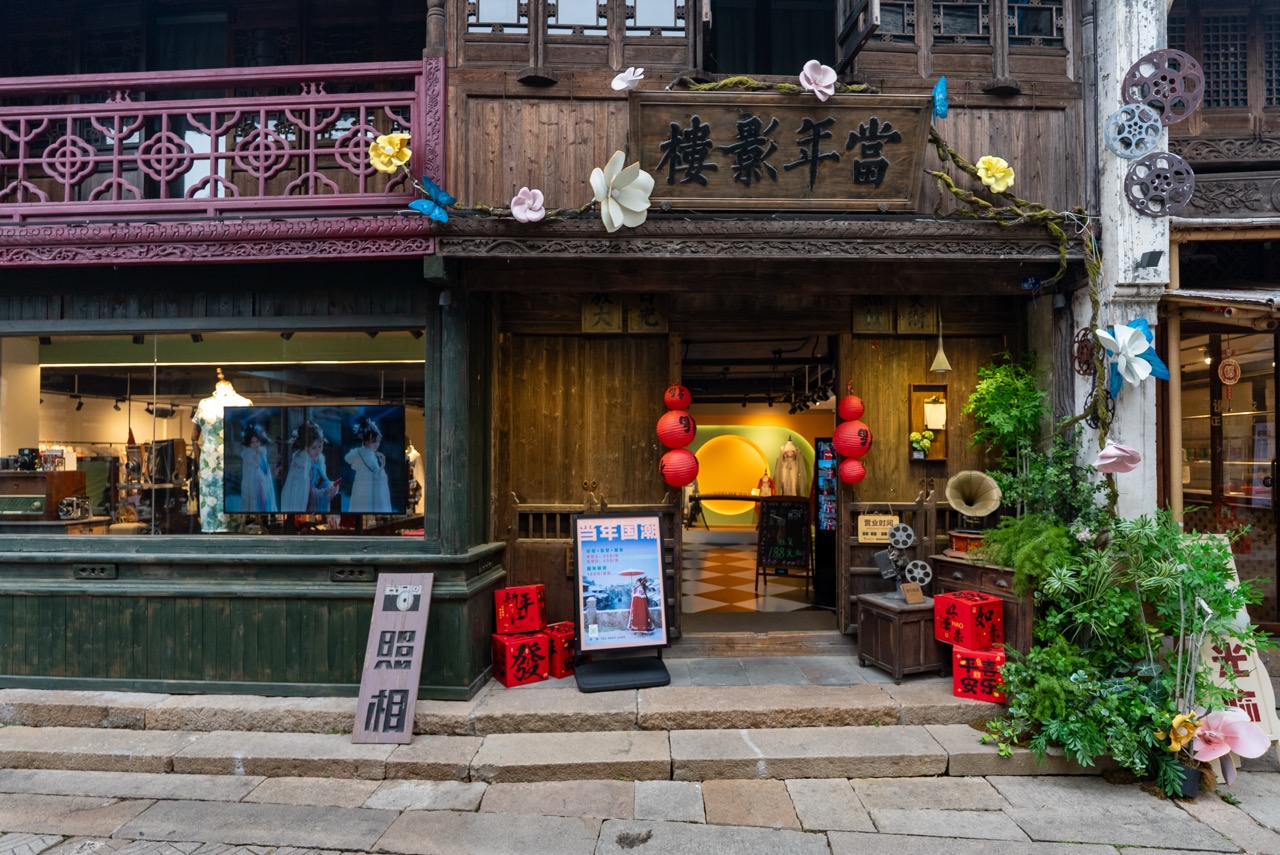 Vintage wooden photo shop facade decorated with lanterns, film reels and paper flowers.