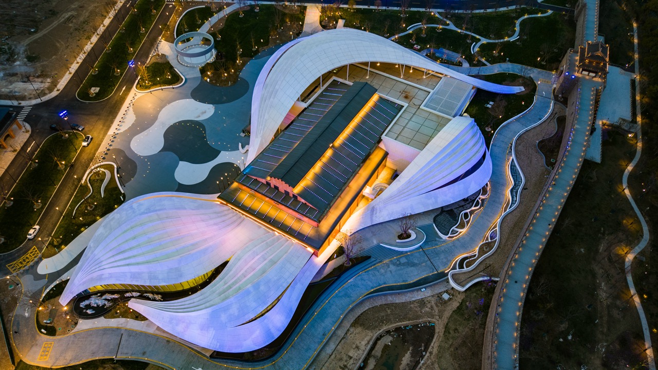 Bird’s-eye perspective capturing overlapping white wave roof panels and winding surrounding walkways.