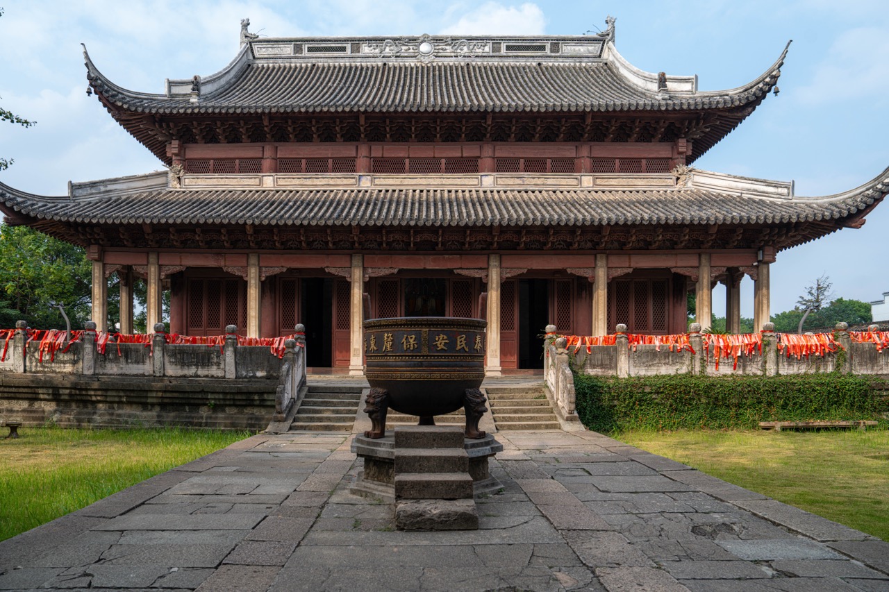 Double-eave ancient wooden sea god temple hall with giant bronze censer in front courtyard.