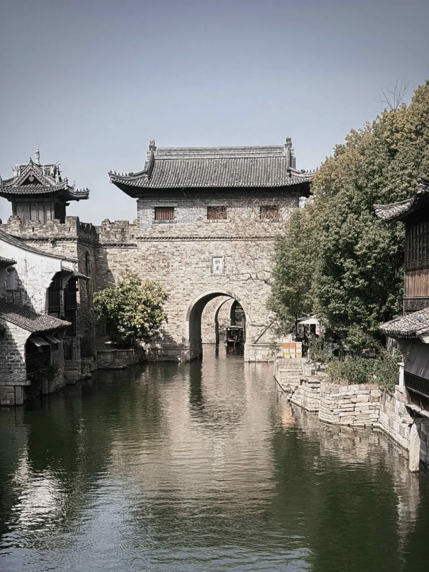 600-year-old stone water gate with canal and boats in Yanguan ancient town.