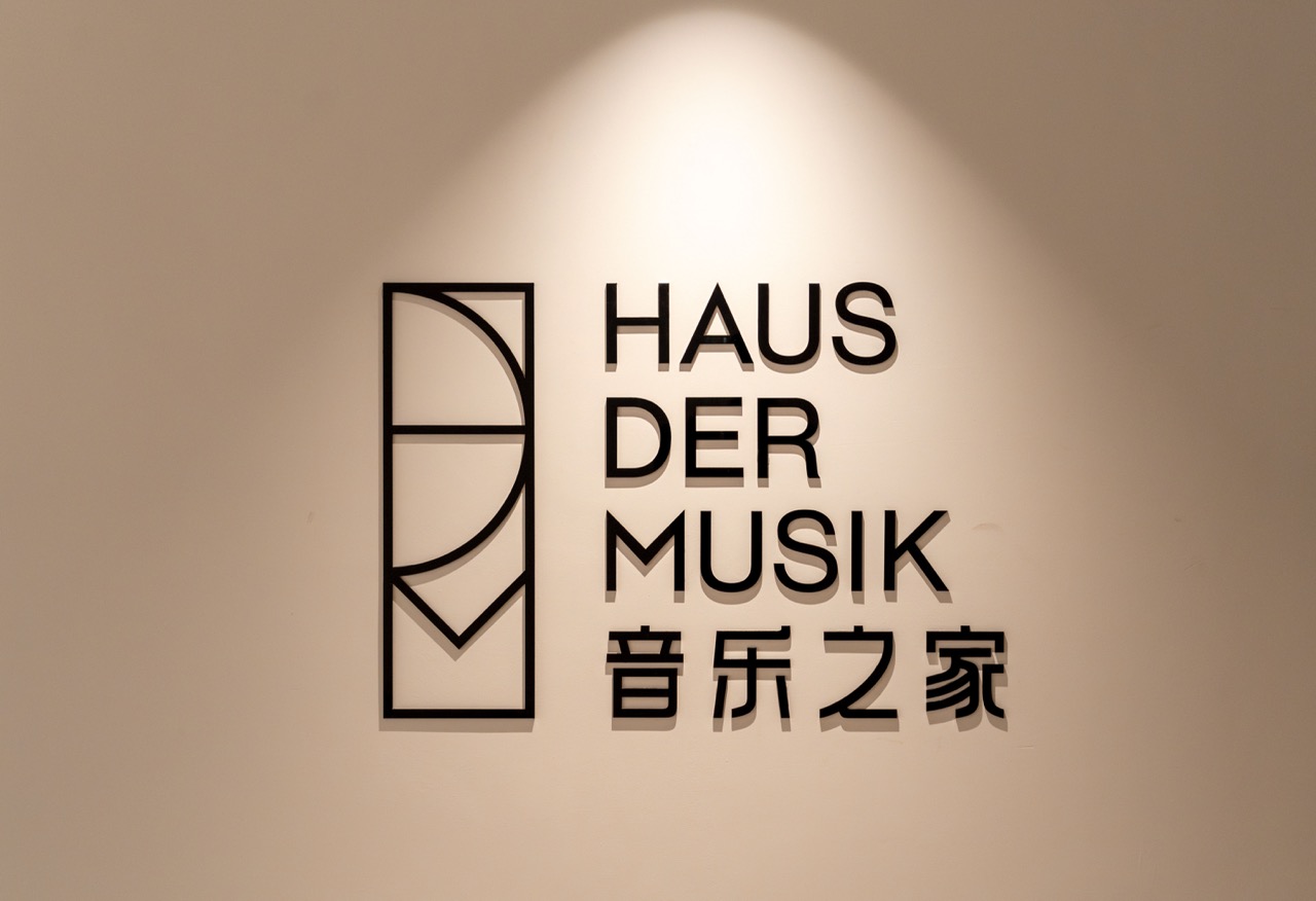 Minimalist wall sign with German "HAUS DER MUSIK" and Chinese "音乐之家" 3D metal lettering.