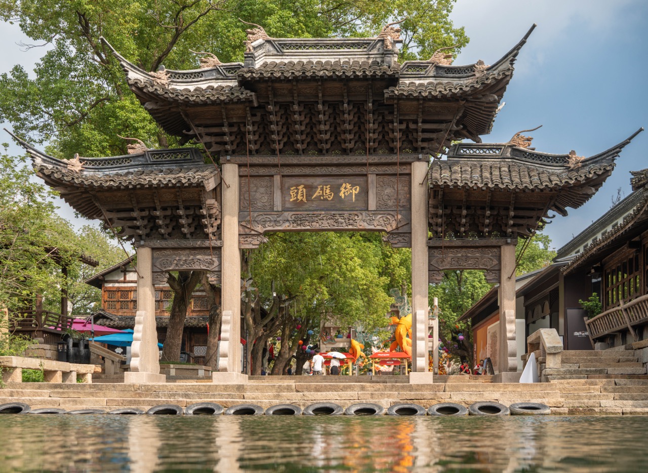 Multi-layer carved timber archway marked "Imperial Pier" facing calm canal water.